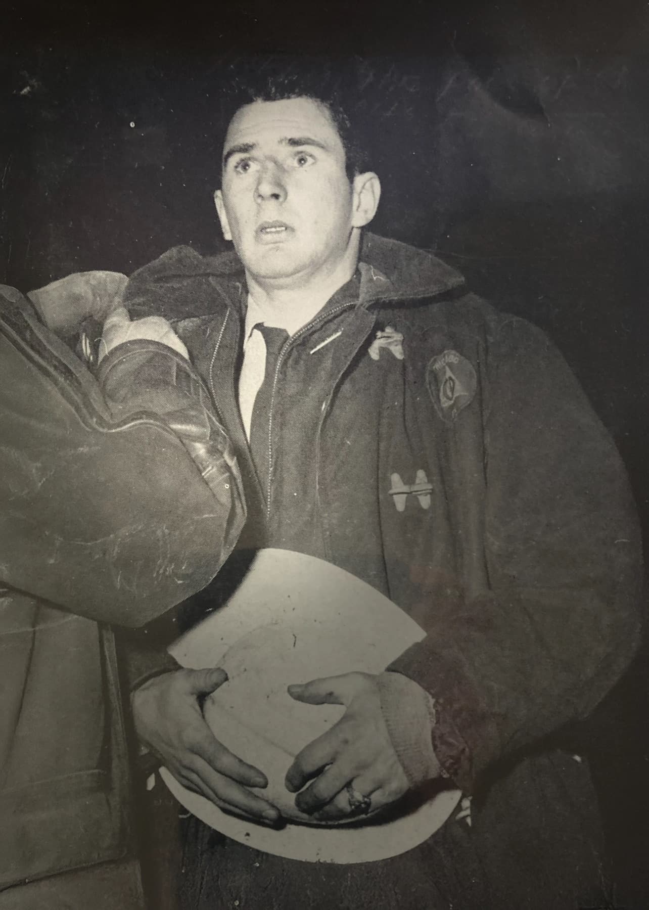 A young man in a coat holding a fire helmet.