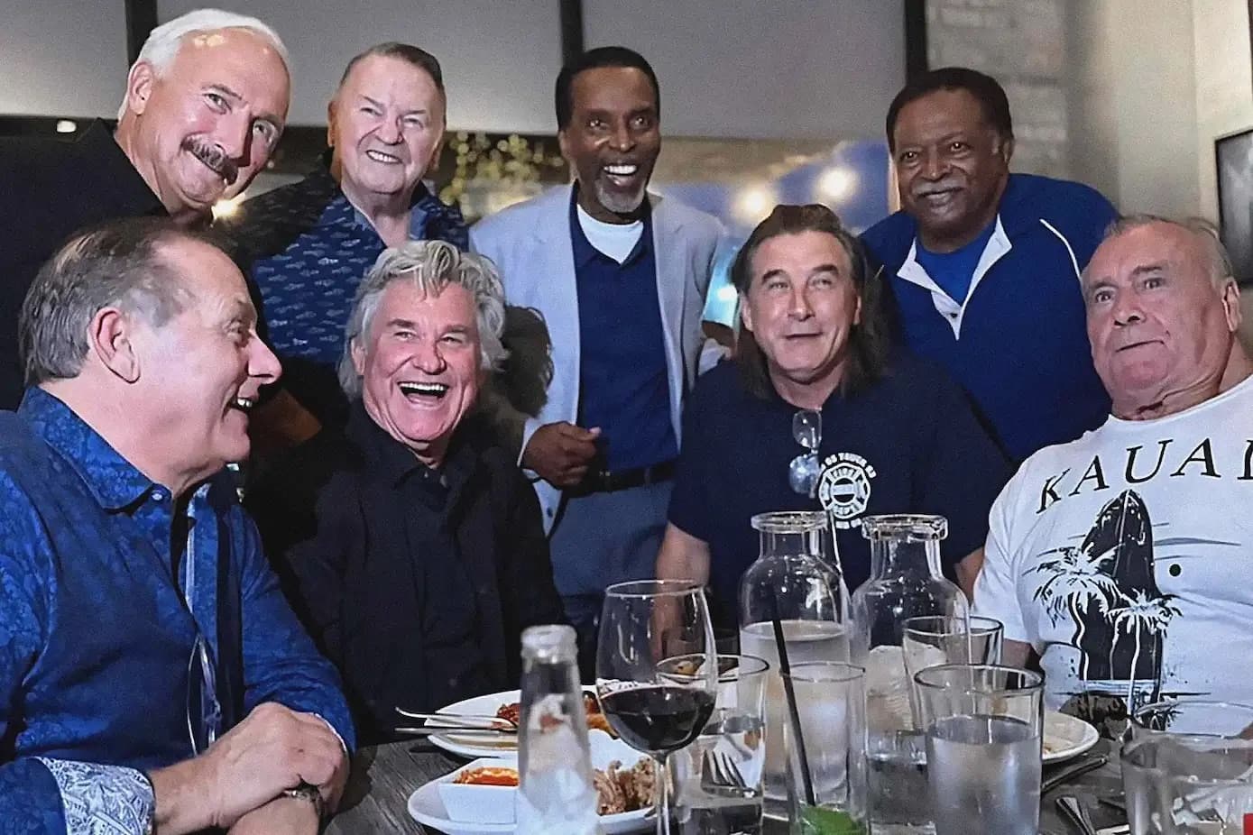 The cast and firefighters laughing around a restaurant table